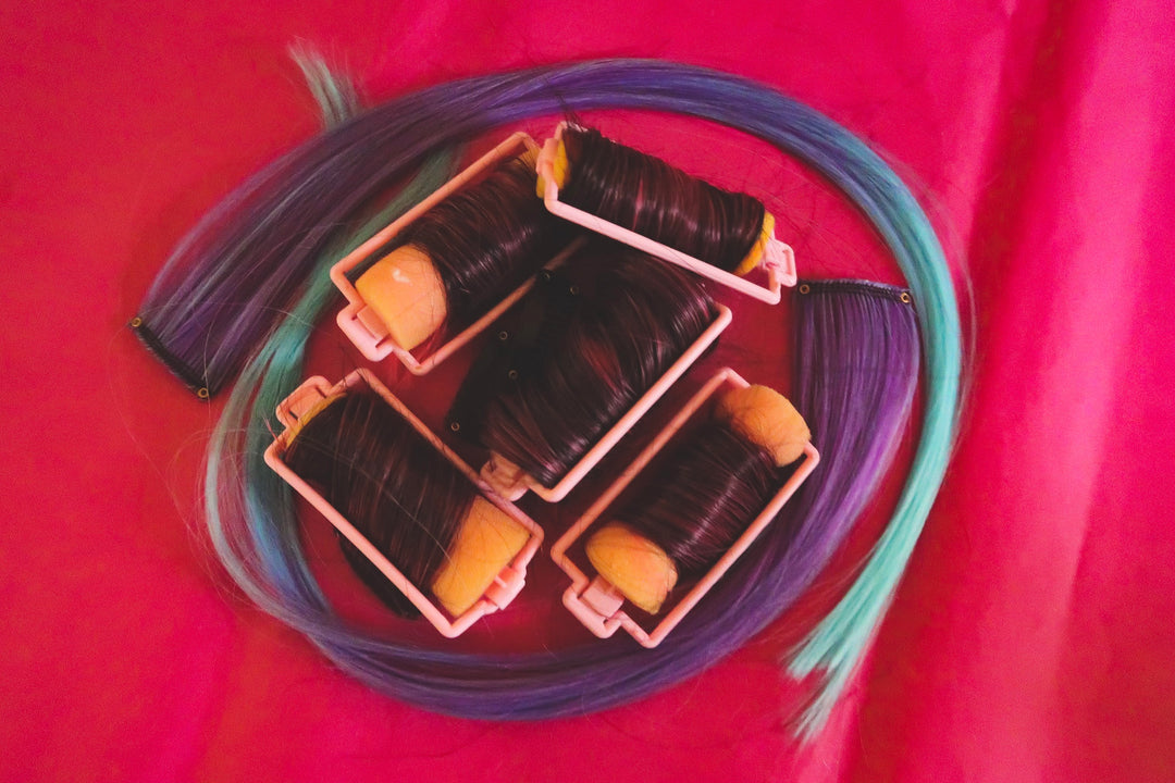 Sponge rollers on a red background with hair extensions being curled overnight.