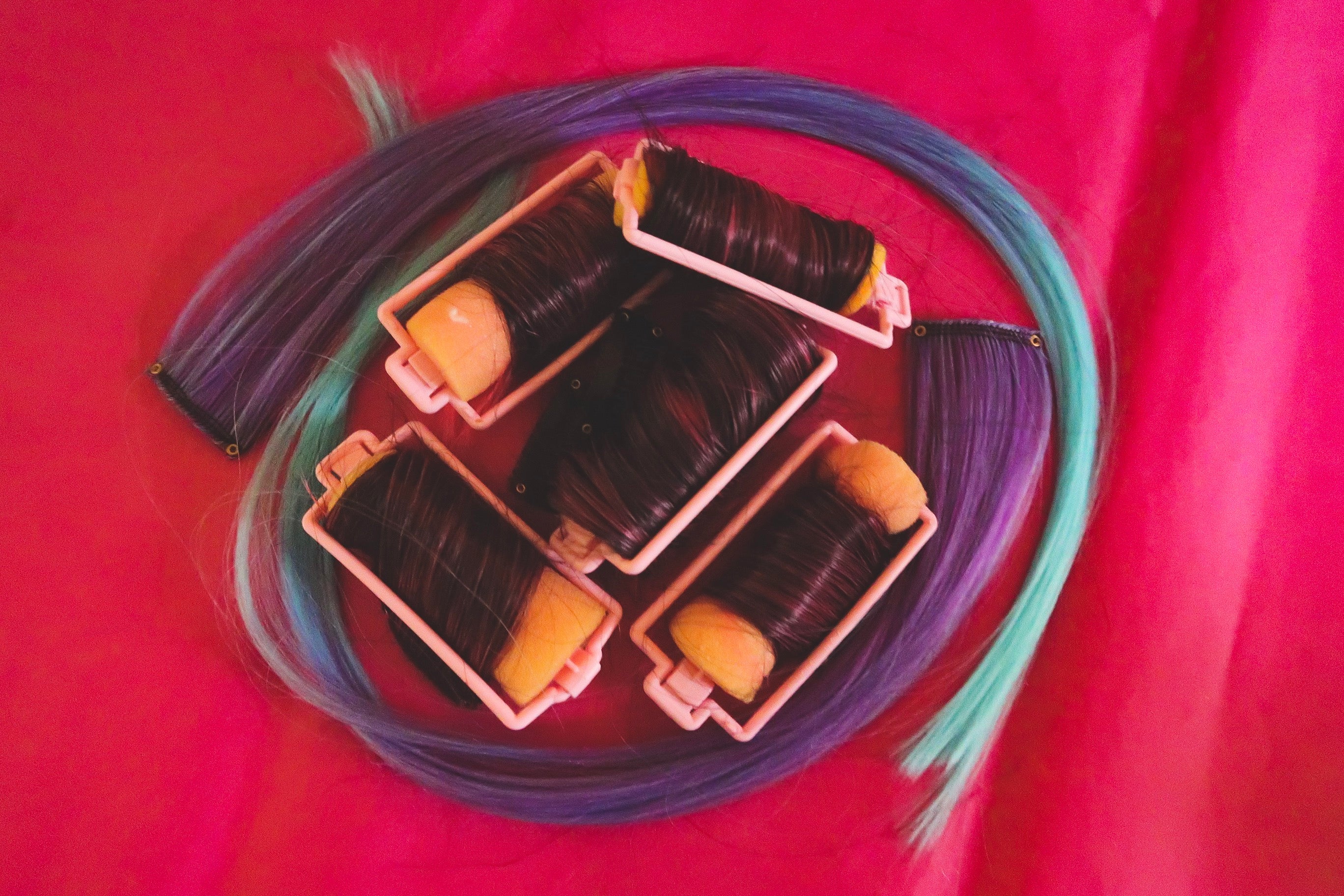 Sponge rollers on a red background with hair extensions being curled overnight.