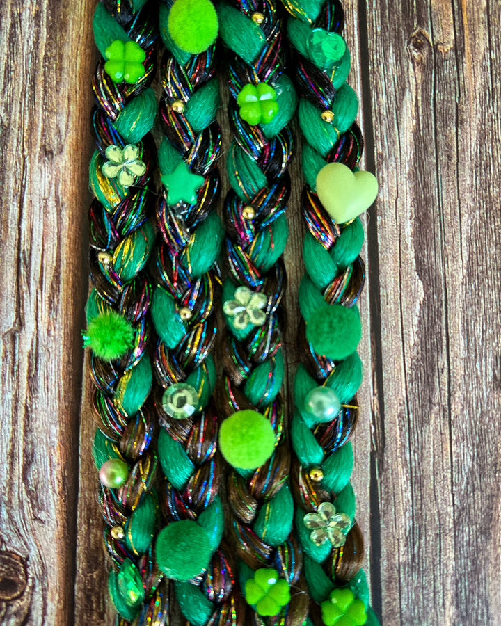 Green braided hair extensions with decorative elements on a wooden background
