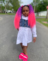 Little girl poses wearing purple and pink wavy tie-on ponytail extensions 