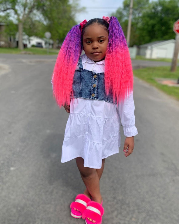 Little girl poses wearing purple and pink wavy tie-on ponytail extensions 